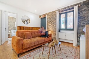 A living room with a sofa, a small table, a mirror, and a stone wall. - Stone House Rochinha by Homie (Funchal)