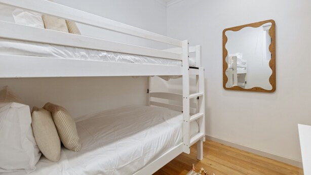 A bunk bed room with a wooden floor, white walls, and a mirror with a wooden frame. - Stone House Rochinha by Homie (Funchal)