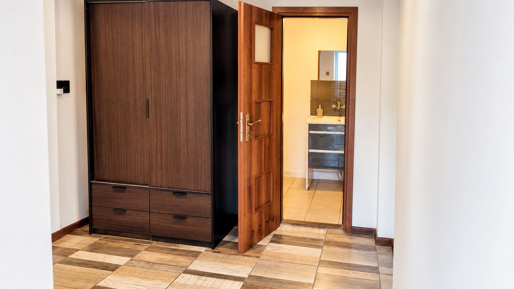 Una habitación con armario, una puerta que da al baño y suelo de baldosas.