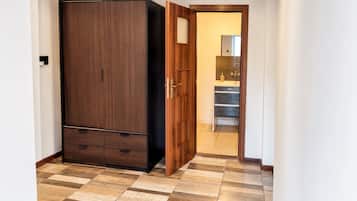 A room with a wardrobe, a door leading to a bathroom, and a tiled floor.