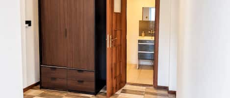 Ein Zimmer mit Kleiderschrank, einer Tür zu einem Badezimmer und einem Fliesenboden.