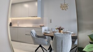 A modern kitchen with white cabinets, a dining table with grey chairs, and a hanging light fixture. - SUNSET SAILORS cozy apartment (Benidorm)