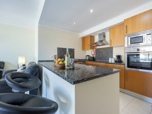A modern kitchen with granite countertops, stainless steel appliances, and wooden cabinets. - Vista das Ondas | Sea View | Olhos d'Água (Olhos de Água)