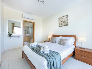 Ein Hotelzimmer mit Bett, Nachttischen, einem Spiegel, einer Dusche und einer Wand-Klimaanlage.
