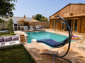 Ein Poolbereich mit Liegestühlen, einer Steinmauer und einem Holzbau.