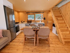 Ein gemütliches Blockhaus-Interieur mit Essbereich, Küche und einer Holztreppe.