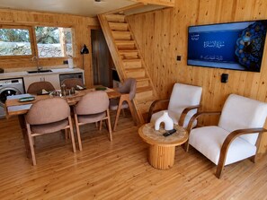 Ein Holzinnenraum mit Essbereich, Stühlen, einem Fernseher und einer Treppe.