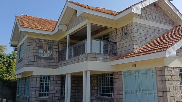 A two-story building with a balcony on the upper floor, a garage door, and a tiled roof.