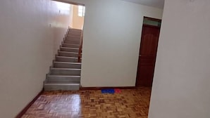 A staircase leading to a door, a patterned floor, and a small window.