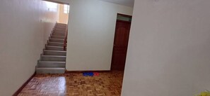 A staircase leading to a door, a patterned floor, and a small window.