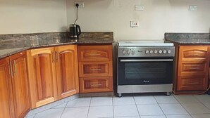 A kitchen with wooden cabinets, a gas stove, and a coffee maker.
