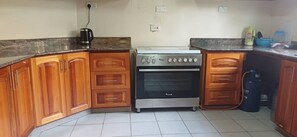 A kitchen with wooden cabinets, a gas stove, and a coffee maker.