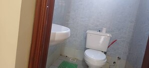 A small bathroom with a toilet, a sink, and a green mat on the floor. - Luxurious 3 bedroom (Nairobi)