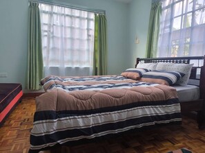 A bedroom with a bed, green curtains, and a wooden floor. - Luxurious 3 bedroom (Nairobi)