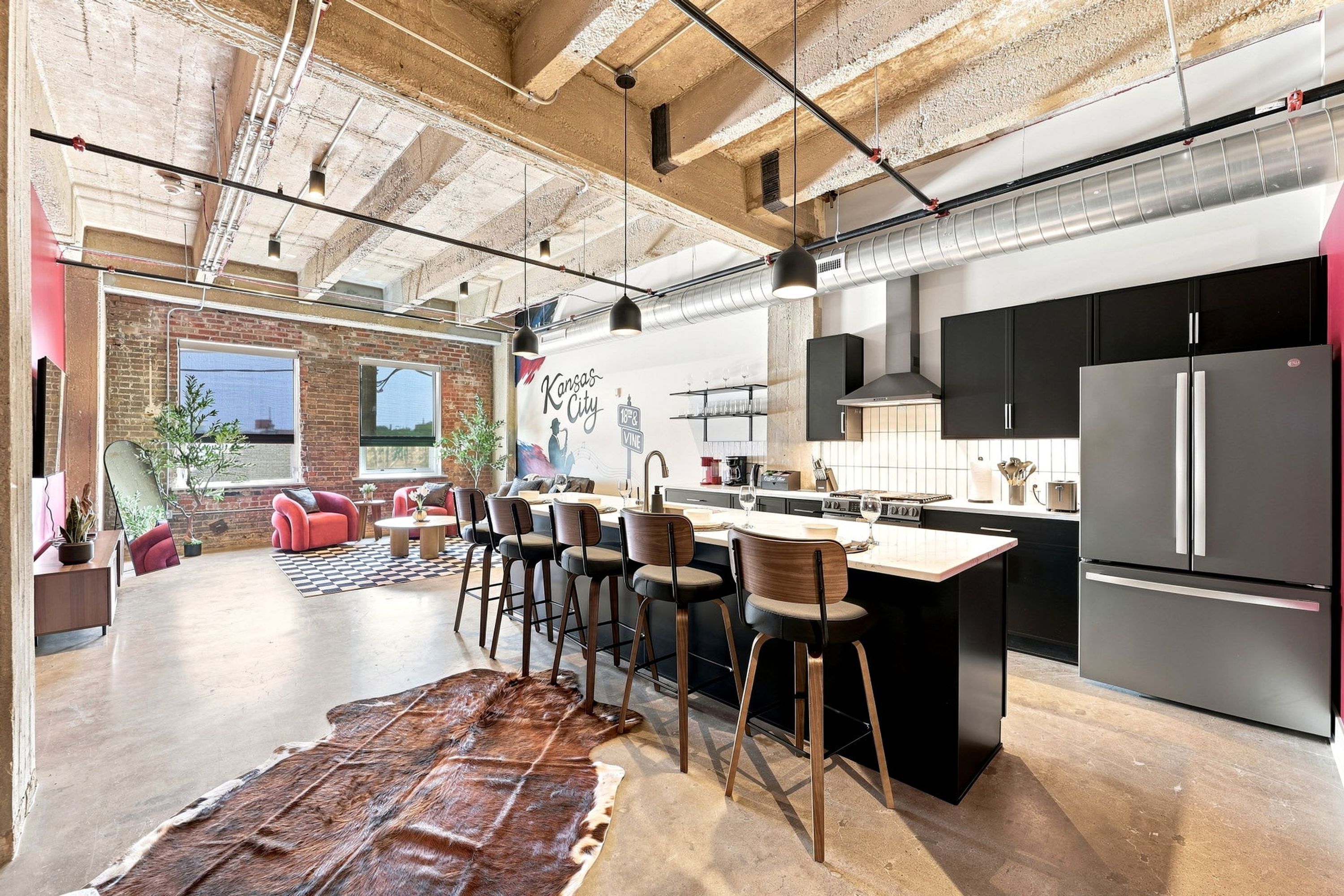 A spacious kitchen with a central island, modern appliances, and a brick wall.
