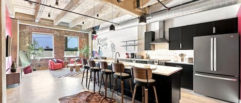 Een ruime keuken met een centraal eiland, moderne apparatuur en een bakstenen muur.