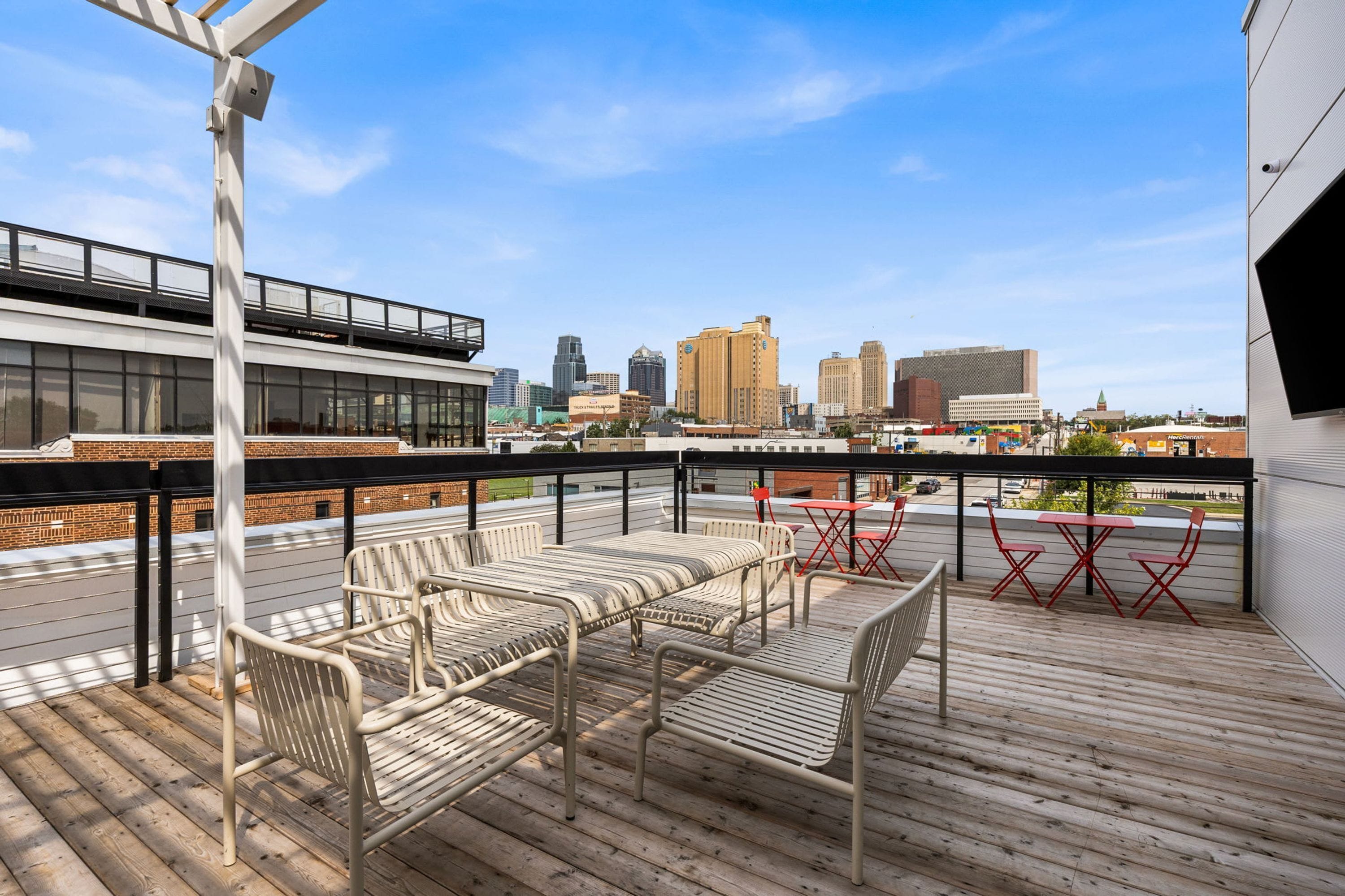 A rooftop terrace with outdoor seating and a city skyline view.