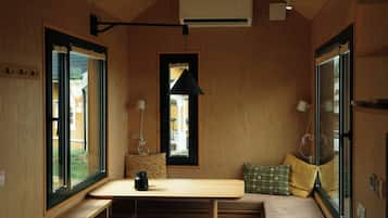 Et rum med træpaneler, et bord, en bænk, et vindue og en hængende lampe.