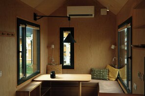 A room with a wooden interior, a table, a bench, a window, and a hanging light fixture.
