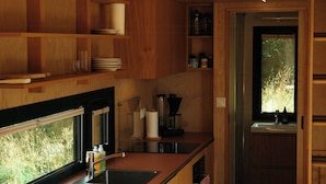 Une cuisine moderne avec des meubles en bois, un four encastré et une fenêtre donnant sur un espace verdoyant.