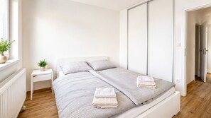 Ein schlicht eingerichtetes Schlafzimmer mit Bett, Nachttisch und einer Topfpflanze.