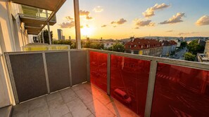 Ein Balkon mit Blick auf eine Stadtlandschaft bei Sonnenuntergang.