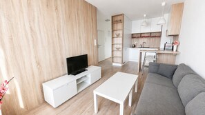 Ein modernes Wohnzimmer mit Fernseher, einem weißen Couchtisch und einem grauen Sofa.