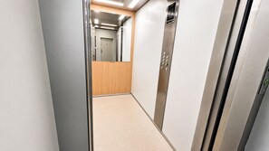 Ein Flur mit Aufzug und einer Tür am Ende.