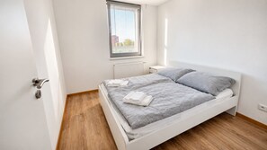 A bedroom with a bed, a radiator, a window, and a door. - AC 2 room apartment with terrace, Prievozska (Bratislava)