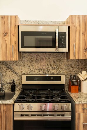A kitchen with a stainless steel stove, a microwave, and wooden cabinets. - NOK Modern 3BR Townhouse in Punta Cana (Punta Cana)