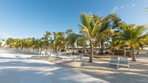 A beach with white lounge chairs and palm trees. - NOK Modern 3BR Townhouse in Punta Cana (Punta Cana)