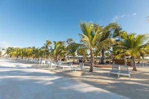 A beach with white lounge chairs and palm trees. - NOK Modern 3BR Townhouse in Punta Cana (Punta Cana)
