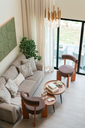 A modern living room with a sofa, two armchairs, a coffee table, and a hanging light fixture. - NOK Modern 3BR Townhouse in Punta Cana (Punta Cana)