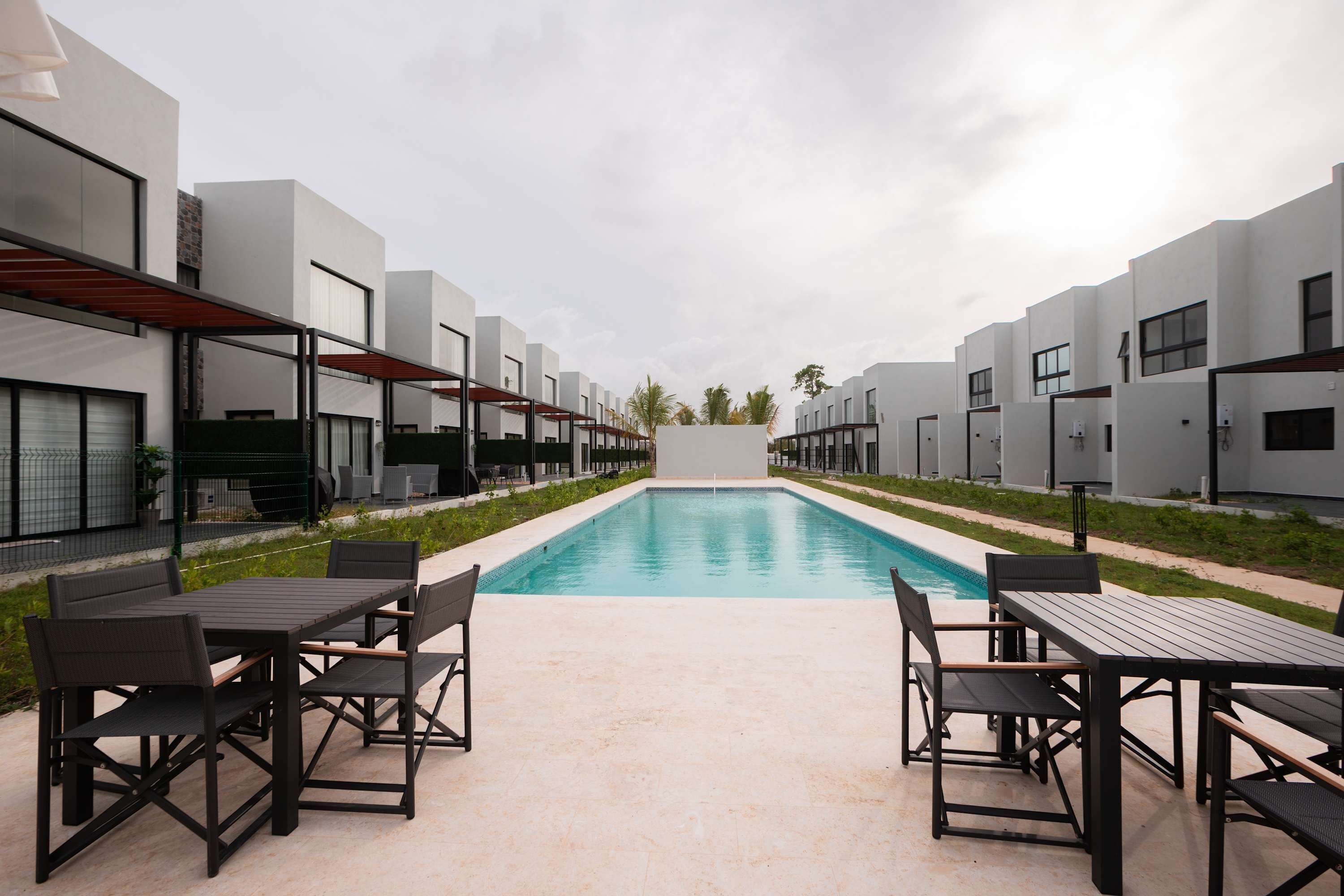 Ein Schwimmbecken mit Terrassenbereich, umgeben von modernen Gebäuden mit großen Fenstern.