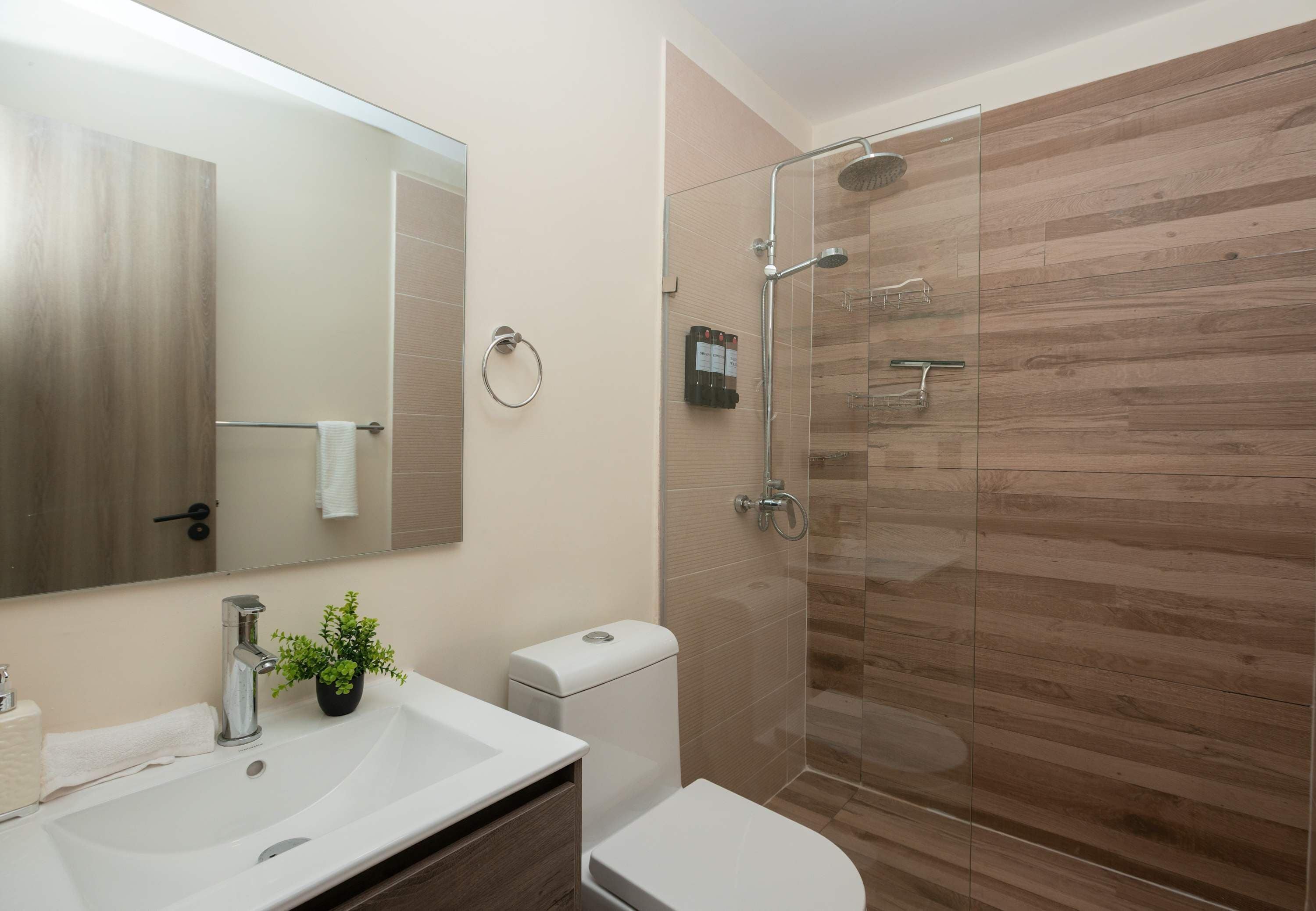 Ein modernes Badezimmer mit einer Duschkabine aus Glas, einem weißen Waschbecken und einer Toilette.