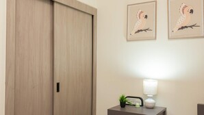 Una habitación con un armario de madera, una mesita de noche con lámpara y dos cuadros en la pared.