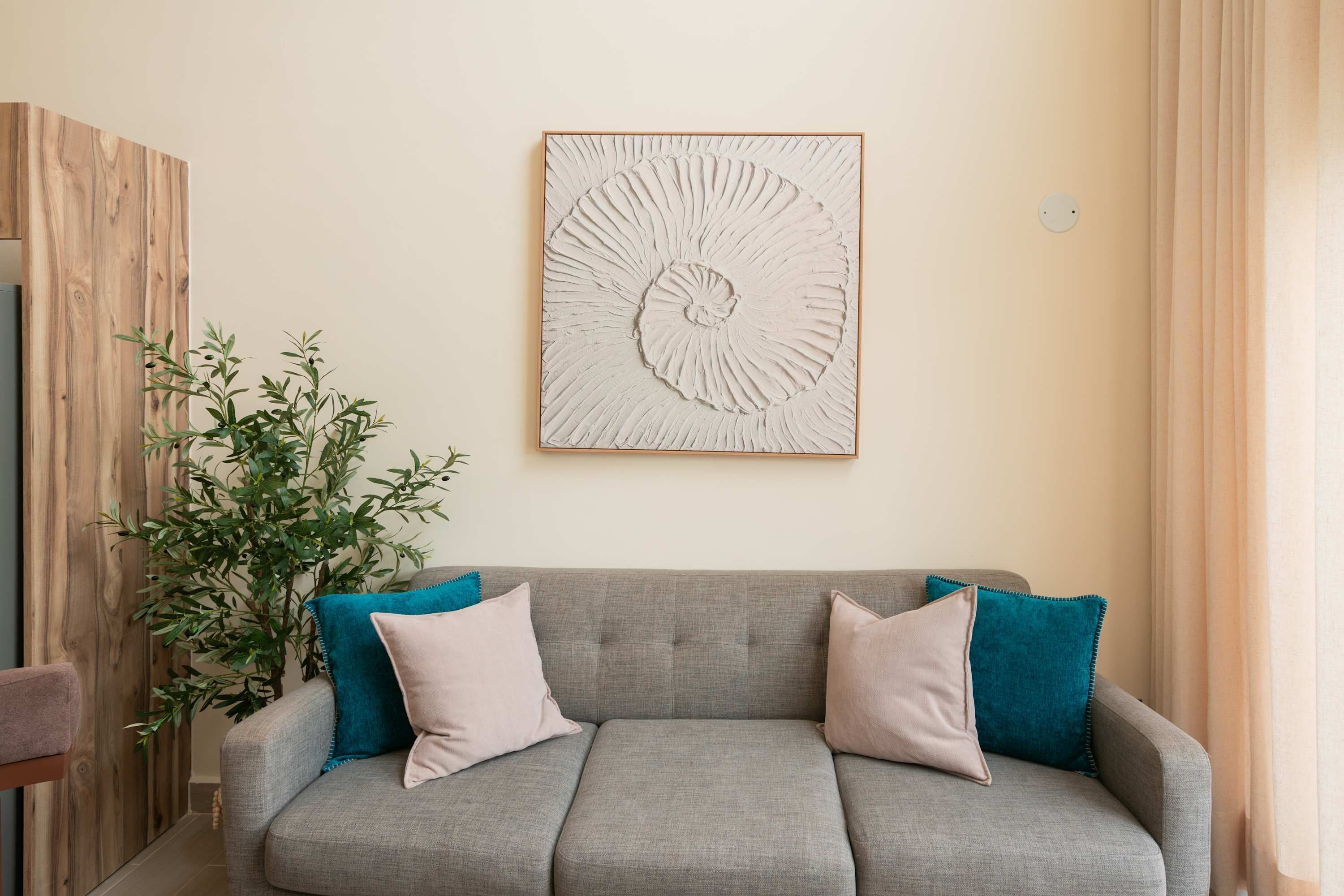 A grey sofa with teal and beige cushions, a wall-mounted artwork, and a wooden accent wall.