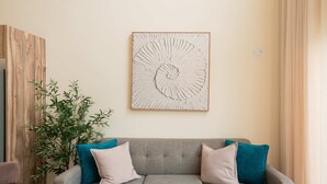 Un sofá gris con cojines verde azulado y beige, una obra de arte colgada en la pared y una pared de acento de madera.