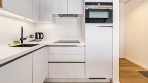 Une cuisine moderne avec des meubles blancs, un four encastré et une machine à café.