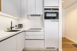 Eine moderne Küche mit weißen Schränken, einem Einbauofen und einer Kaffeemaschine.