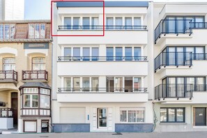 Ein mehrstöckiges Wohngebäude mit einer Garagentür, großen Fenstern und Balkonen.