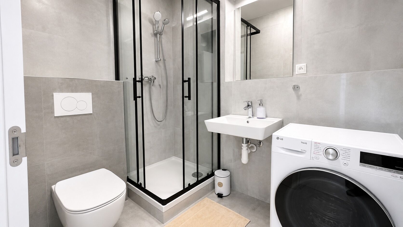 Ein modernes Badezimmer mit einer Duschkabine, einer Toilette, einem Waschbecken und einer Waschmaschine.