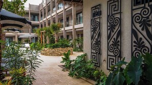A hotel courtyard with a stone pathway, palm trees, and a decorative metal gate. - 5 Minutes to Eagle Beach|Private BBQ| Pool & Jacuzzi (Noord)