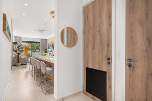Cocina moderna con puerta de madera, un espejo redondo y una barra con taburetes.