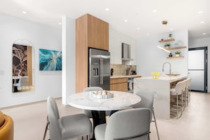 A modern kitchen with a central island, built-in appliances, and a dining area with a round table and chairs. - 5 Minutes to Eagle Beach|Private BBQ| Pool & Jacuzzi (Noord)