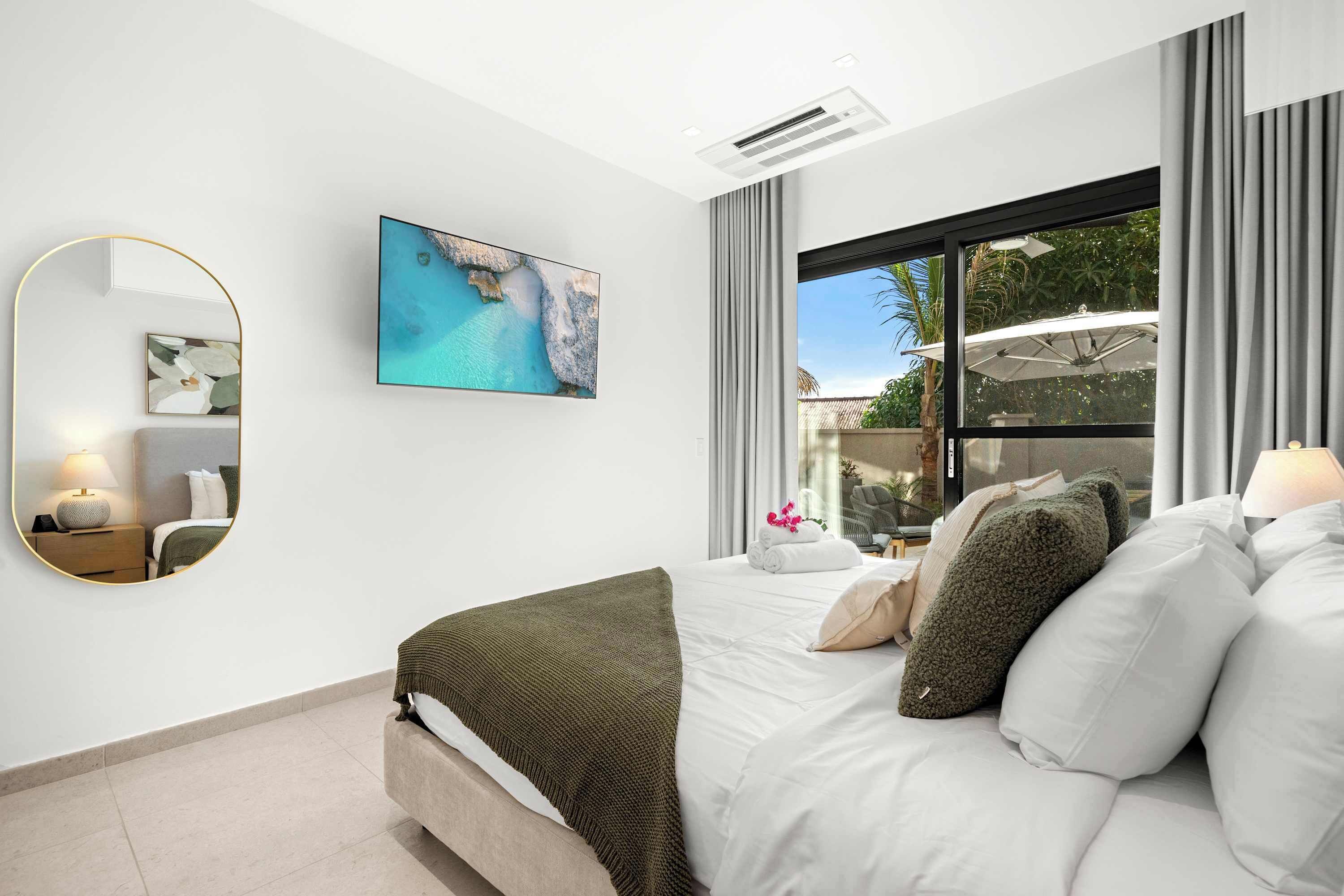 Habitación de hotel moderna con una cama grande, vistas al exterior, una obra de arte colgada y un aire acondicionado en el techo.