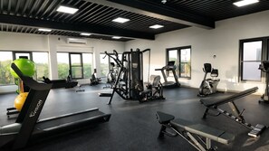 A gym with various exercise equipment, large windows, and a view of greenery. - 5 Minutes to Eagle Beach|Private BBQ| Pool & Jacuzzi (Noord)