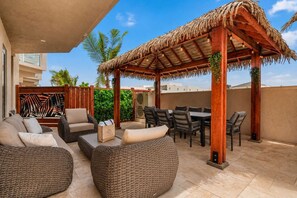 An outdoor patio with wicker furniture, a wooden pergola, and a view of the cityscape. - Private Pool | 2BR Retreat | Near Eagle Beach (Noord)