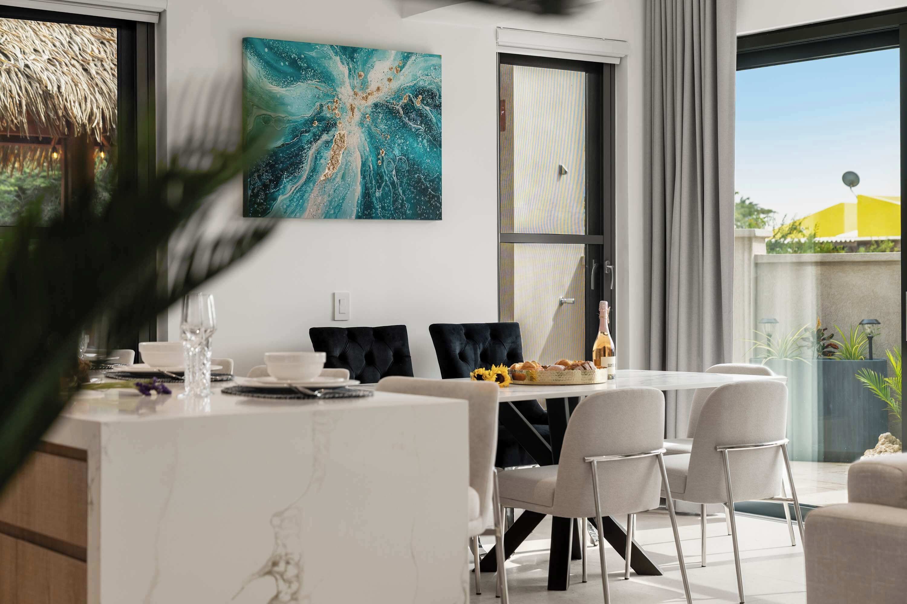 A modern dining area with a white marble table, black upholstered chairs, and a large abstract painting on the wall.