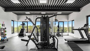 Een moderne sportschool met diverse fitnessapparaten, grote ramen en uitzicht op de omgeving.